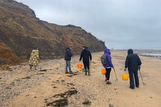 5 people picking up litter along The Naze coastline