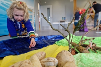 Child playing with shell in sensory tray