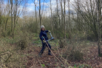 Caroline at a work party posing for the camera in the middle of a woodland