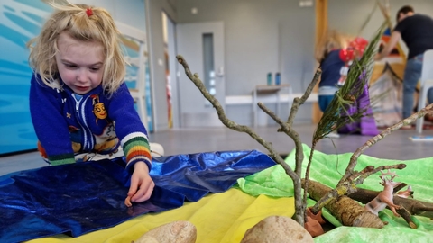 Child playing with shell in sensory tray