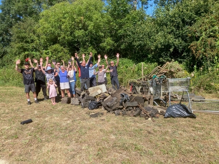 Volunteers standing with arms raised in celebration next to a pile of collected rubbish